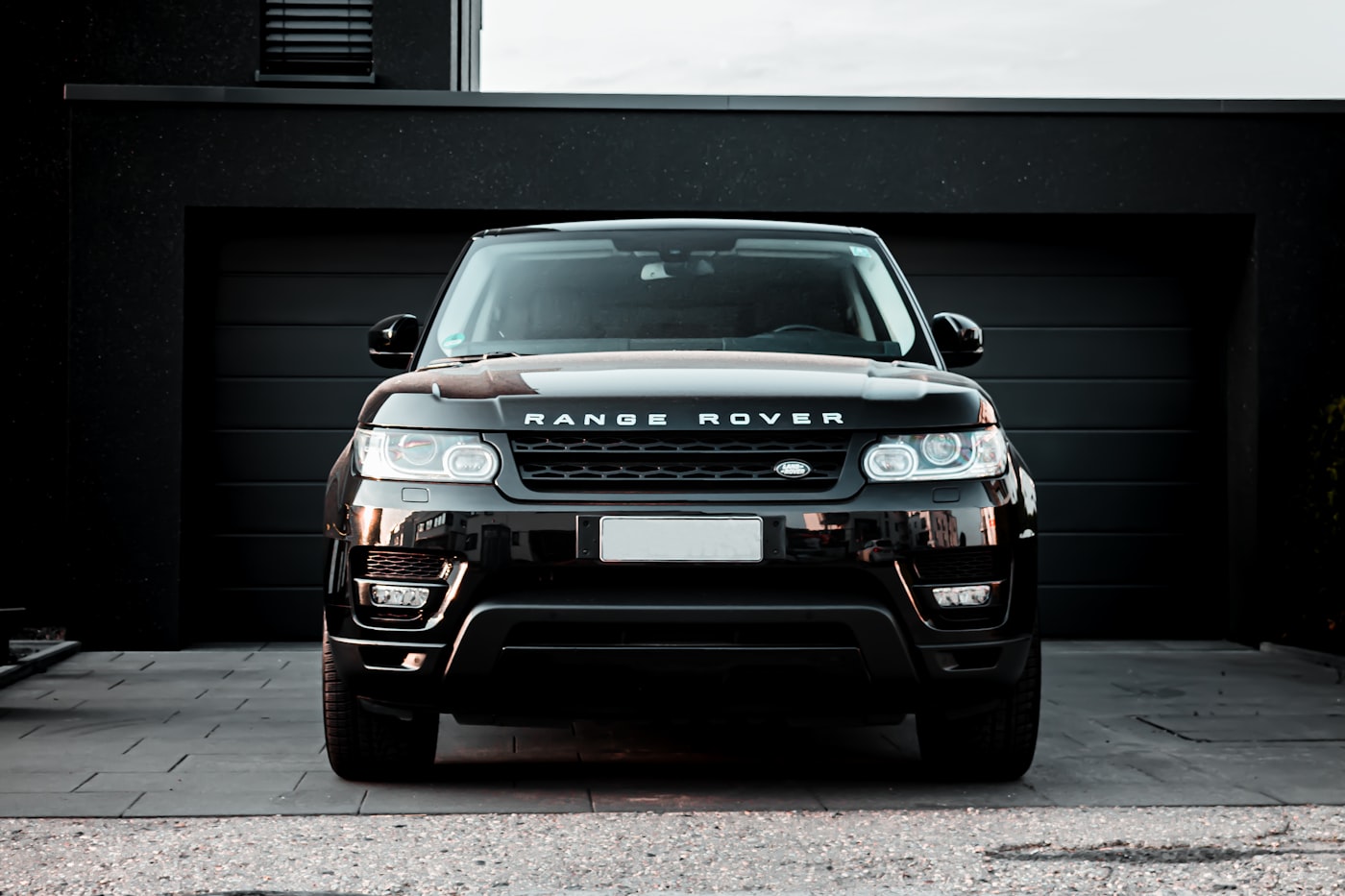 Range Rover Sport noir devant un garage privé contemporain